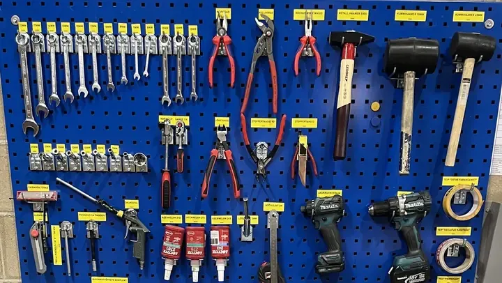 Shadow board with wrenches, pliers and hammers, each under its own yellow label